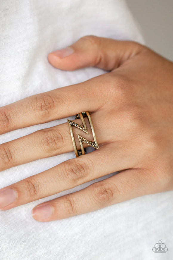 Paparazzi 5th Avenue Flash - Brass Ring - Dotted in sections of dainty aurum rhinestones, glistening brass bars zigzag across the finger, coalescing into an edgy band. Features a dainty stretchy band for a flexible fit.
