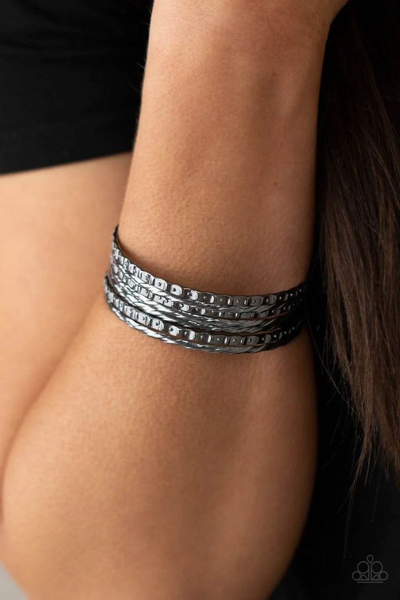Embossed in slanted ribbons of textured and studded hammered patterns, trios of mismatched gunmetal bangles stack across the wrist for an intense industrial vibe.  Sold as one set of six bracelets.