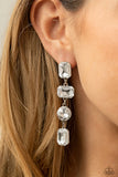 Paparazzi Cosmic Heiress - White Earrings - A strand of oversized round, teardrop, and emerald cut rhinestones trickles from the ear, creating a jaw-dropping chandelier. Earring attaches to a standard post earring.