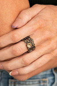 Paparazzi Ebb And GLOW - Brass Ring - An oversized topaz rhinestone adorns a leafy brass backdrop of two topaz rhinestone dotted bands, coalescing into a whimsical centerpiece. Features a stretchy band for a flexible fit.