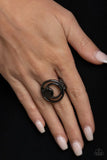 Paparazzi Edgy Eclipse - Black Gunmetal - Ring - A solid gunmetal disc and airy gunmetal hoops eclipse across the finger, delicately coalescing into an edgy offset frame. Features a stretchy band for a flexible fit.