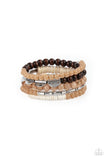 Mismatched sections of glassy and opaque brown beads join silver discs, brown wooden beads, and white disc-like beads along a coiled wire, creating an earthy infinity wrap bracelet around the wrist.