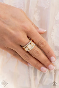 Paparazzi Majestically Mythic - Gold Ring - A trio of round champagne cat’s eye stones is set in gold pronged fittings between two dainty gold bands that are encrusted in rows of glassy white rhinestones, coalescing into an elegantly layered centerpiece atop the finger. Features a dainty stretchy band for a flexible fit.
