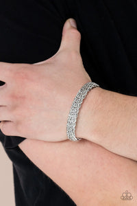 Twisting silver wires interlock across the wrist, creating a thickly woven cuff.