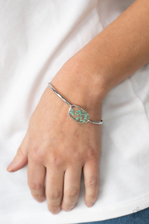 Paparazzi Prairie Paradise - Blue Bracelet - Encased inside an asymmetrical glass casing, a dainty blue firework flower centerpiece attaches to two arcing silver bars around the wrist for a whimsical floral look. Features an adjustable clasp closure.