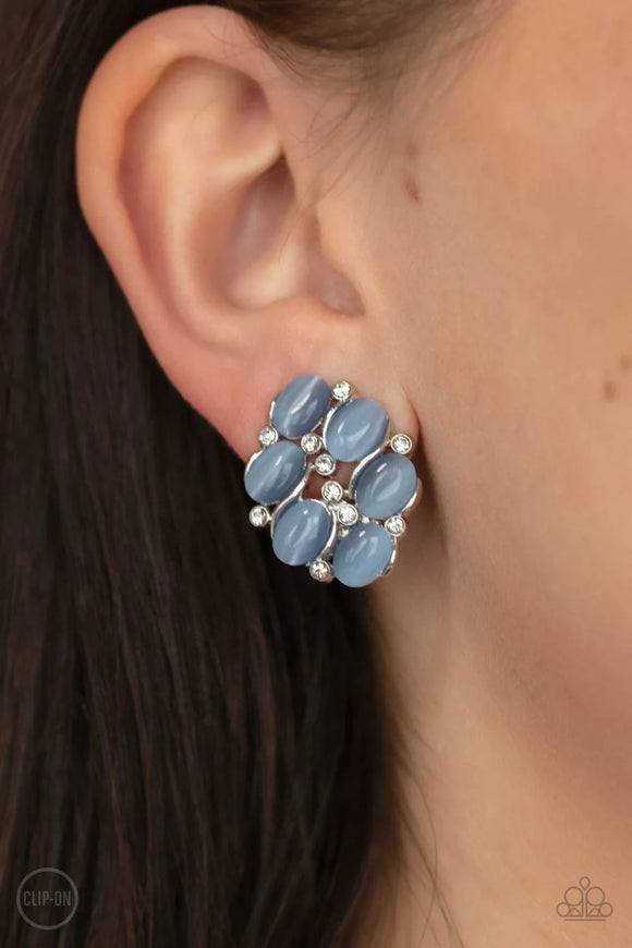 Paparazzi Row Row Row Your Yacht - Blue Clip-On Earrings - A glassy collection of dainty white rhinestones and Cerulean cat's eye stones coalesce into a bubbly frame for a timeless look. Earring attaches to a standard clip-on fitting.