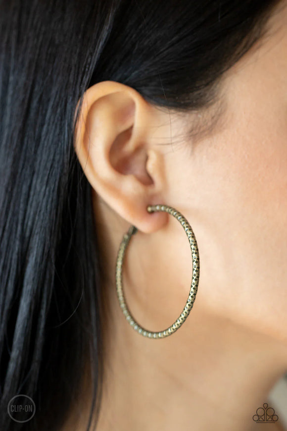 Paparazzi Subtly Sassy - Brass Clip-On Earrings - An oversized brass hoop featuring a porous-like texture sends off a subtle shimmer as it wraps around the ear. Earring attaches to a standard clip-on fitting. Hoop measures approximately 2
