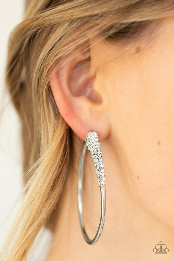 Paparazzi Winter Ice  -  As if dipped in glitter, a rhinestone encrusted frame swings from the ear in a dramatic fashion. Hoop measures 1 1/2€� in diameter. Earring attaches to a standard post fitting.
