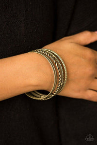 Paparazzi When The Going Gets Rough - Brass Delicately hammered and etched in tribal inspired patterns, mismatched brass bangles stack across the wrist for an indigenous look. Flat brass studs are pressed into one bangle for a perfect splash of metallic shimmer.

