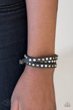 Paparazzi Lets Go For A CATWALK - Black - Bracelet  -  A skinny strip of black leather is encrusted in sections of glittery white rhinestones and flat brass, gold, and silver studs. The elongated band double wraps around the wrist for a fierce one-of-a-kind look. Features an adjustable snap closure.