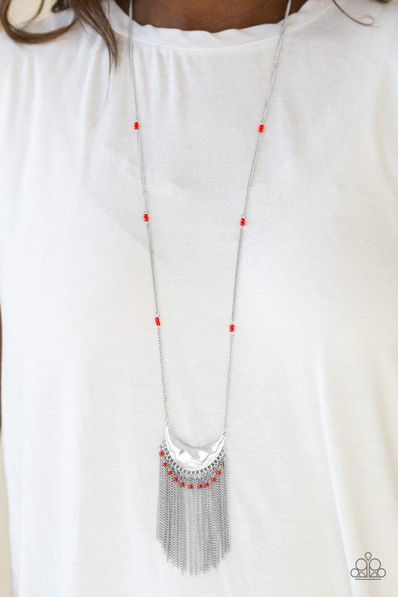Paparazzi Desert Trance- Red A delicately hammered silver crescent swings from the bottom of an elongated silver chain infused with red seed bead accents. The tribal inspired pendant gives way to a shimmery fringe sprinkled with more seed beads for a wanderlust finish. Features an adjustable clasp closure.

