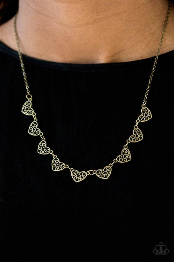 Paparazzi Love And Devotion- Brass Heart-shaped filigree dances along the centers of shimmery brass heart frames. The airy frames delicately connect below the collar for a chic finish. Features an adjustable clasp closure.

