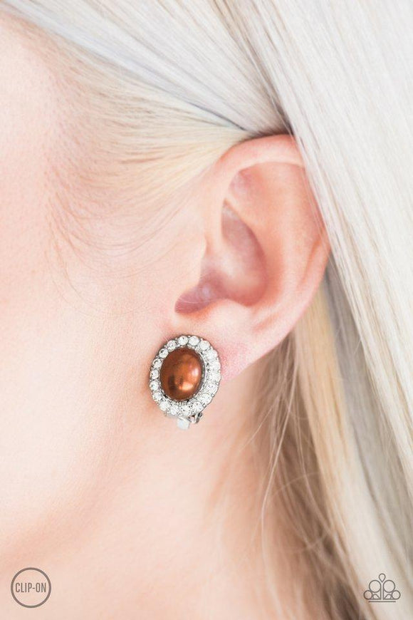 Paparazzi Romantically Regal - Brown A pearly brown bead is pressed into the center of a white rhinestone encrusted frame for a timeless look. Earring attaches to a standard clip-on fitting.

