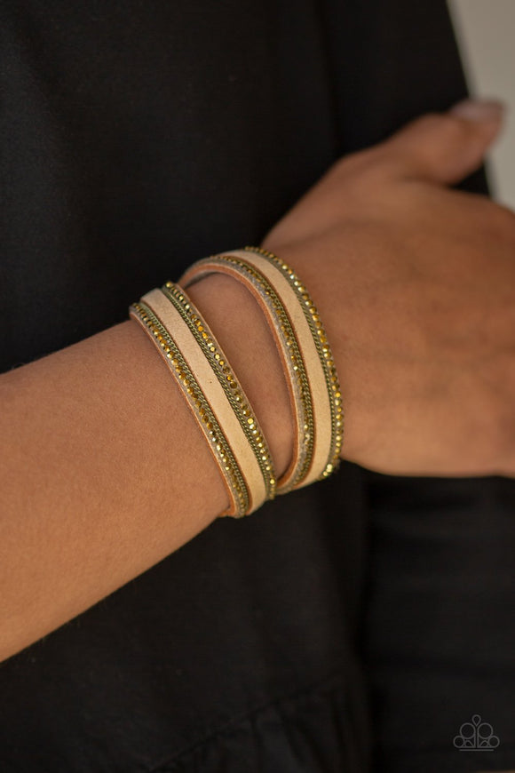Paparazzi Going For Glam - Brass An elongated tan suede band is encrusted in rows of glassy aurum rhinestones and shimmery brass chains. The elongated band double wraps around the wrist for a fierce one-of-a-kind look. Features an adjustable snap closure.
