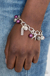 Paparazzi Lady Love Dove - Purple Purple pearls, ornate silver beads, and white rhinestone encrusted accents swing from a dramatic silver chain. A shimmery silver bird charm and silver tassel are added to the display, creating a whimsical fringe around the wrist. Features an adjustable clasp closure.
