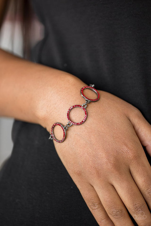 Paparazzi Dress The Part - Red - Bracelet  -  Encrusted in fiery red rhinestones, three glittery gunmetal rings link across the wrist for a glamorous look. Features an adjustable clasp closure.
