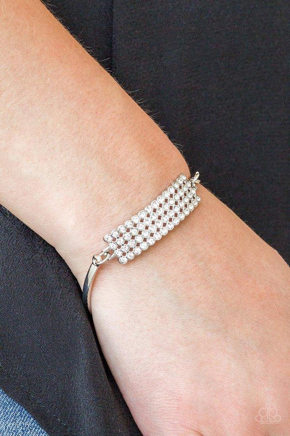 Paparazzi Top Class Class- White Row after row of glassy white rhinestones stack into a gorgeous rectangular pendant. Attached to two arcing silver bars, the glittery pendant sits atop the wrist for an undeniably glamorous look. Features an adjustable clasp closure.


