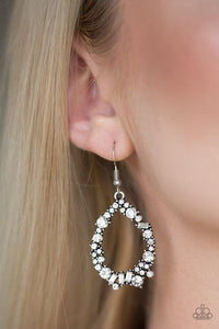 Paparazzi Crushing Couture - White Featuring classic round and edgy emerald style cuts, glassy white rhinestones are encrusted along a silver teardrop frame for a sassy look. Earring attaches to a standard fishhook fitting.

