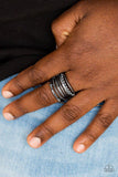 Paparazzi The STEEL Of Night - Black Featuring smooth, dotted, and textured finishes, mismatched gunmetal bands layer across the finger for a bold industrial look. Features a stretchy band for a flexible fit.
