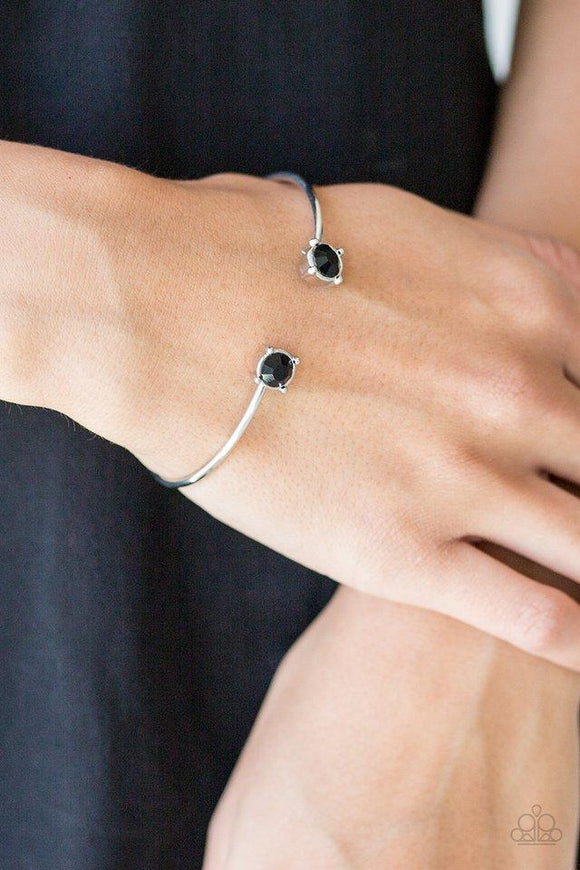Paparazzi New Traditions - Black Attached to a curling silver bar, glittery black rhinestones are pressed into silver fittings, creating a dainty cuff.


