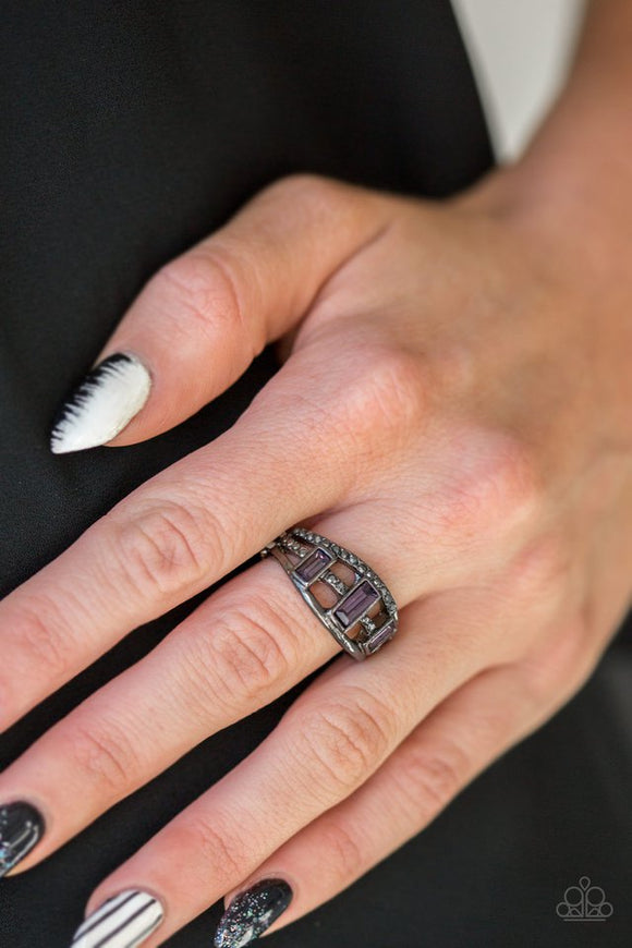 Paparazzi Noble Nova - Purple - Ring  -  Three purple emerald-cut rhinestones are encrusted along three gunmetal bands radiating with smooth surfaces and sections of glittery hematite rhinestones for an edgy fashion. Features a stretchy band for a flexible fit.

