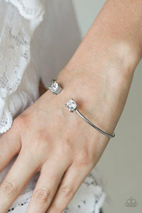 Paparazzi New Traditions - White Attached to a curling silver bar, glittery white rhinestones are pressed into silver fittings, creating a dainty cuff.

