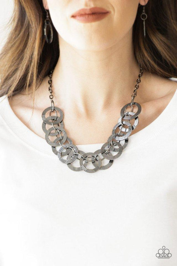 Paparazzi The Main Contender - Black  -  Etched and hammered in linear and diamond-cut shimmer, glistening gunmetal circles interlock into a bold industrial chain below the collar. Features an adjustable clasp closure.
