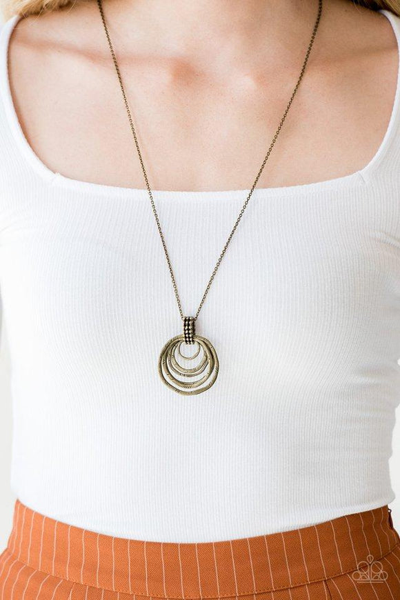 Paparazzi Rippling Relic - Brass Etched in serrated textures, glistening brass rings swing from the bottom of a studded brass fitting. The rippling pendant swings from the bottom of a lengthened brass chain for a seasonal finish. Features an adjustable clasp closure.

