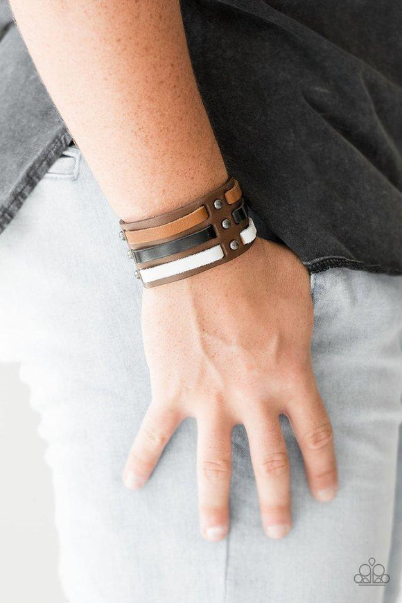 Paparazzi Grizzly Ground - Multi Strips of black, brown, and white leather are laced through a thick brown leather band radiating with gunmetal studs for a rugged look. Features an adjustable snap closure.

