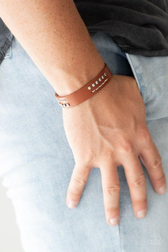 Paparazzi Always An Adventure - Brown Sections of shimmery silver studs and stitched white thread adorns the front of a brown leather band for an adventurous look. Features an adjustable snap closure.

