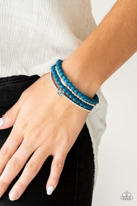 Paparazzi Blooming Buttercups - Blue - Bracelet  -  Mismatched silver beads and strands of glassy blue beads are threaded along stretchy bands. Infused with silver accents, dainty rose blossoms adorn the wrist for a seasonal finish.
