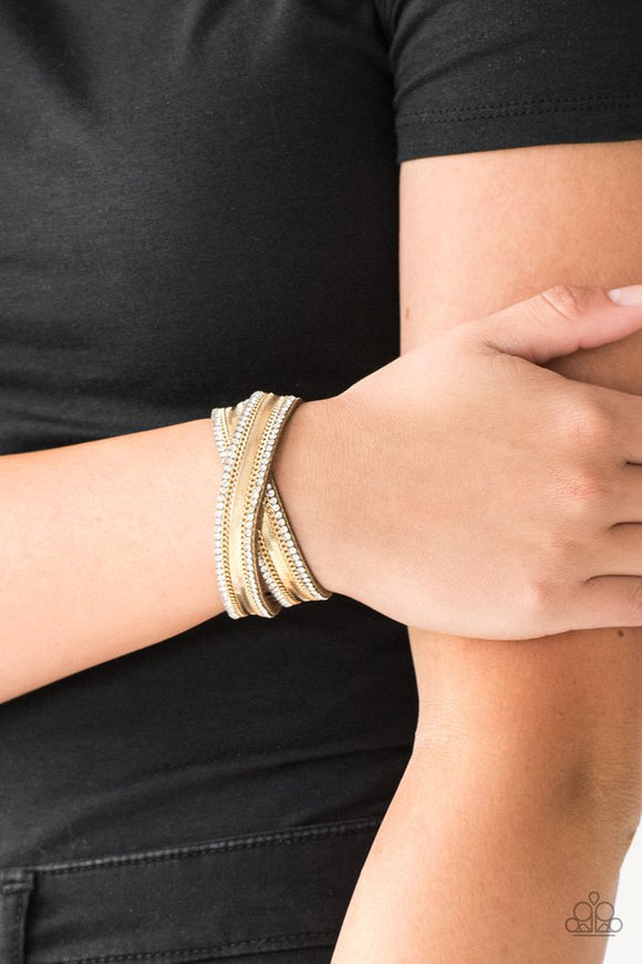 Paparazzi Rocker Rivalry - Gold - Bracelet  -  Rows of classic gold chain, flat gold chain, and dainty white rhinestones are encrusted along a suede band dusted in golden sparkles for a sassy look. The elongated band allows for a trendy double wrap design. Features an adjustable snap closure.
