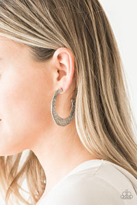 Paparazzi The HOOP Up - Silver  -  Radiating with hammered detail, an asymmetrical silver hoop curls around the ear for a casual look. Earring attaches to a standard post fitting. Hoop measures 2" in diameter.

