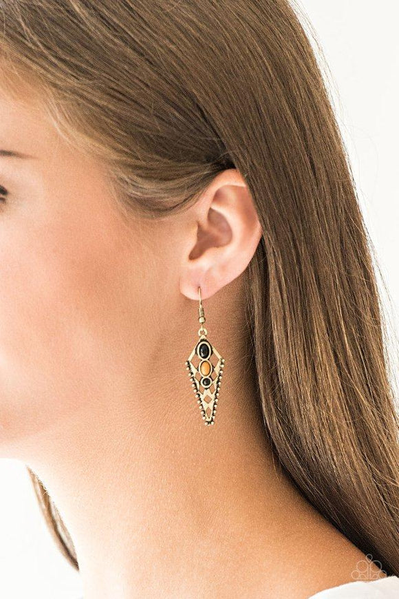 Paparazzi Terra Territory - Brass Varying in shape, three dainty black and Meerkat beads are encrusted down the center of an ornate triangular frame for a tribal inspired look. Earring attaches to a standard fishhook fitting.

