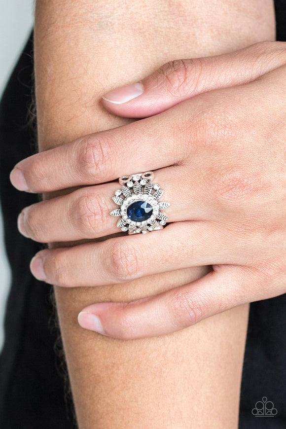 Paparazzi Burn Bright - Blue - Ring
Ringed in glittery white rhinestones, a glittery blue gem is pressed into the center of a leafy silver frame. Dainty white rhinestones are sprinkled along the shimmery foliage for a refined finish. Features a stretchy band for a flexible fit.
