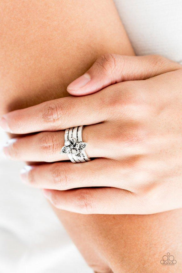 Paparazzi Island Icon - Silver A leafy flower blooms from the center of a thick silver band rippling with hammered and linear textures. Features a stretchy band for a flexible fit.

