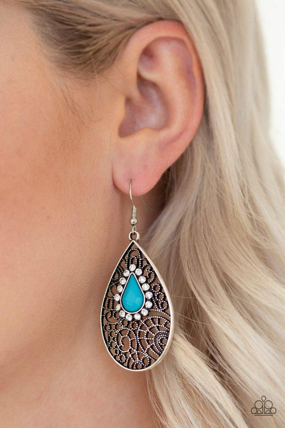 Paparazzi Modern Monte Carlo - Blue  -  Ringed in glassy white rhinestones, a teardrop blue bead is pressed into a shimmery silver frame radiating with airy filigree for a refined fashion. Earring attaches to a standard fishhook fitting.
