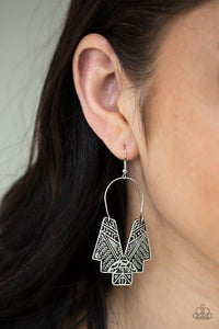 Paparazzi Alternative ARTIFACTS - Silver Embossed in tactile tribal inspired patterns, an abstract geometric frame swings from a silver wire fitting for a tribal inspired look. Earring attaches to a standard fishhook fitting.

