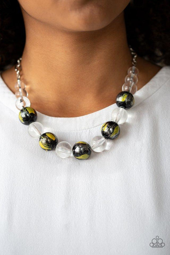 Paparazzi Torrid Tide - Yellow A collection of shiny black and glassy clear beads are threaded along an invisible wire below the collar. The black beads are splashed in hints of bright yellow and shiny metallic paint for a colorful finish. Features an adjustable clasp closure.

