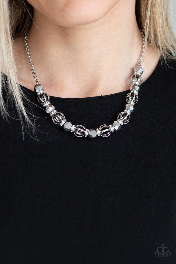 Paparazzi Metro Majestic - Silver A collection of airy silver beads, glittery hematite rhinestone beads, and white rhinestone encrusted rings are threaded along an invisible wire below the collar for a statement-making fashion. Features an adjustable clasp closure.

