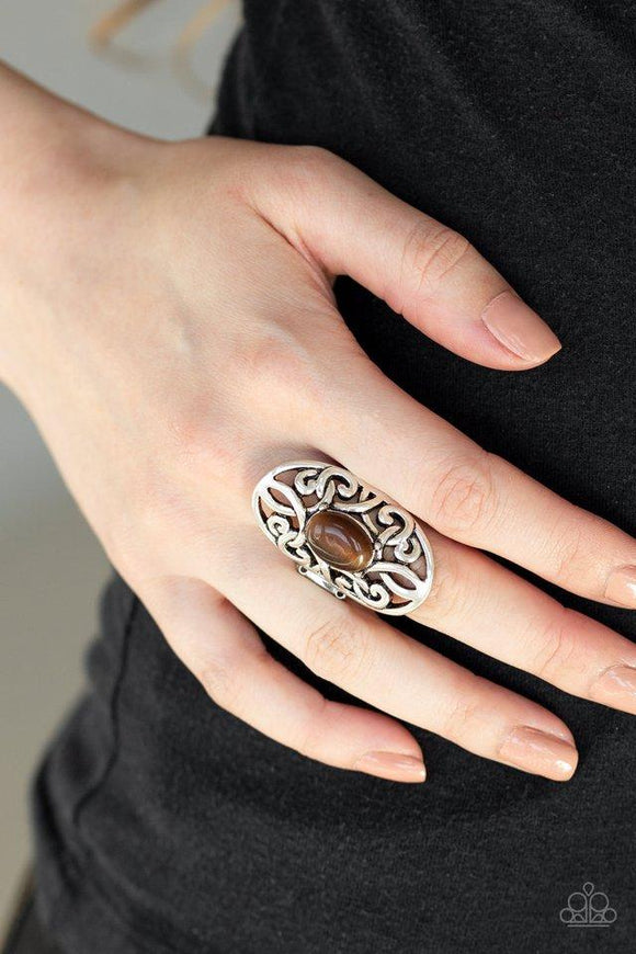 Paparazzi GLEAM Big - Brown  -  A glowing brown cat's eye stone is pressed into the center of an oval backdrop swirling with vine-like filigree for a whimsical look. Features a stretchy band for a flexible fit.
