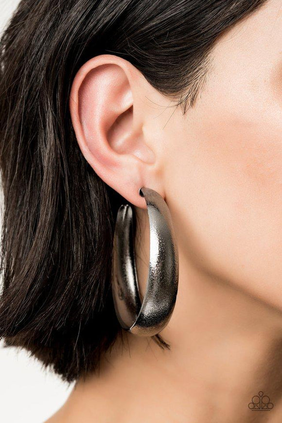 Paparazzi HOOPS I Did It Again - Black - 2019 Convention Exclusive
Hammered in blinding shimmer, a thick gunmetal hoop curls around the ear for a grunge-glamorous look. Earring attaches to a standard post fitting. Hoop measures approximately 2 1/4
