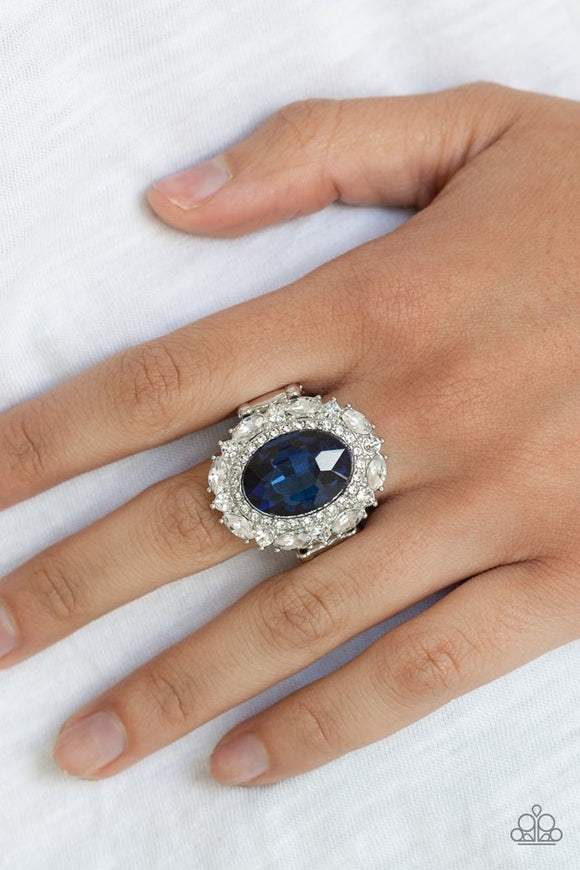 Paparazzi Show Glam - Blue - Ring  -  An oversized oval blue gem is pressed into the center of a round silver frame encrusted in mismatched white rhinestones for a glamorous look. Features a stretchy band for a flexible fit.
