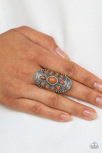 Paparazzi Stone Sunrise - Brown Embossed in a studded filigree pattern, an oval silver frame folds around the finger. Featuring round, oval, and teardrop shapes, earthy brown stone beads are pressed into the center of the frame, creating a whimsical floral pattern. Features a stretchy band for a flexible fit.

