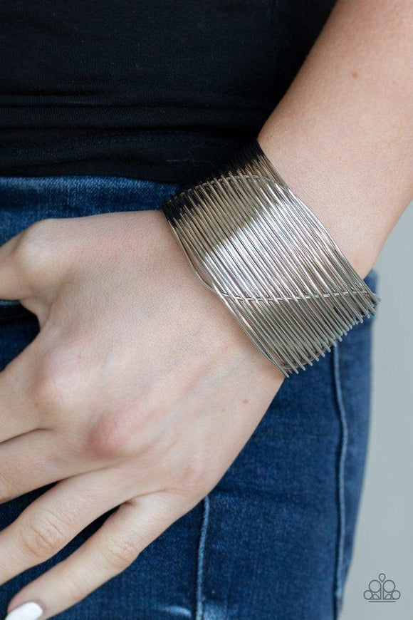 Paparazzi Retro Revamp - Silver A glistening silver wire weaves through stacked silver bars arcing across the wrist, coalescing into an edgy cuff.
