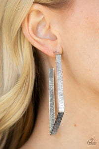 Paparazzi Way Over The Edge - Silver  -  Hammered in a glittery finish, a flat silver ribbon bends into an asymmetrical hoop for an edgy look. Earring attaches to a standard post fitting. Hoop measures approximately 1 1/2" in diameter.

