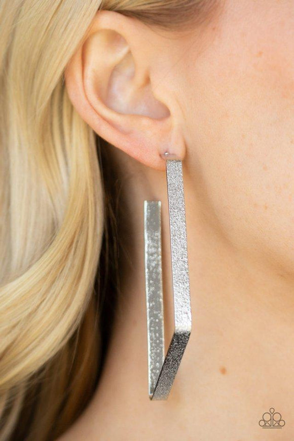 Paparazzi Way Over The Edge - Silver  -  Hammered in a glittery finish, a flat silver ribbon bends into an asymmetrical hoop for an edgy look. Earring attaches to a standard post fitting. Hoop measures approximately 1 1/2