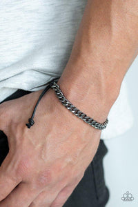 Paparazzi Hurrah - Black  -  Shiny black cording knots around the ends of a gunmetal beveled curb chain that is wrapped across the top of the wrist for a versatile look. Features an adjustable sliding knot closure.
