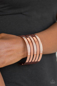 Paparazzi Big Time Shine - Copper Smooth shiny copper and glittery white rhinestone encrusted shiny copper bands alternate across the wrist, stacking into a statement-making cuff.
