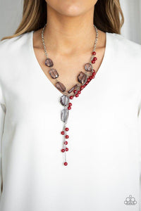 Paparazzi Prismatic Princess - Red Featuring an array of shapes and cuts, a collection of faceted smoky gems link below the collar for a glamorous shimmer. A shimmery silver strand of pearly red beads trickles down one side of the piece, creating a flirtatious extended pendant. Features an adjustable clasp closure.
